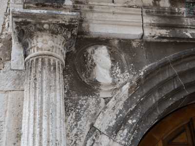 Su questi edifici appaiono infatti due medaglioni che mostrano un giovane viso maschile con corona di alloro...